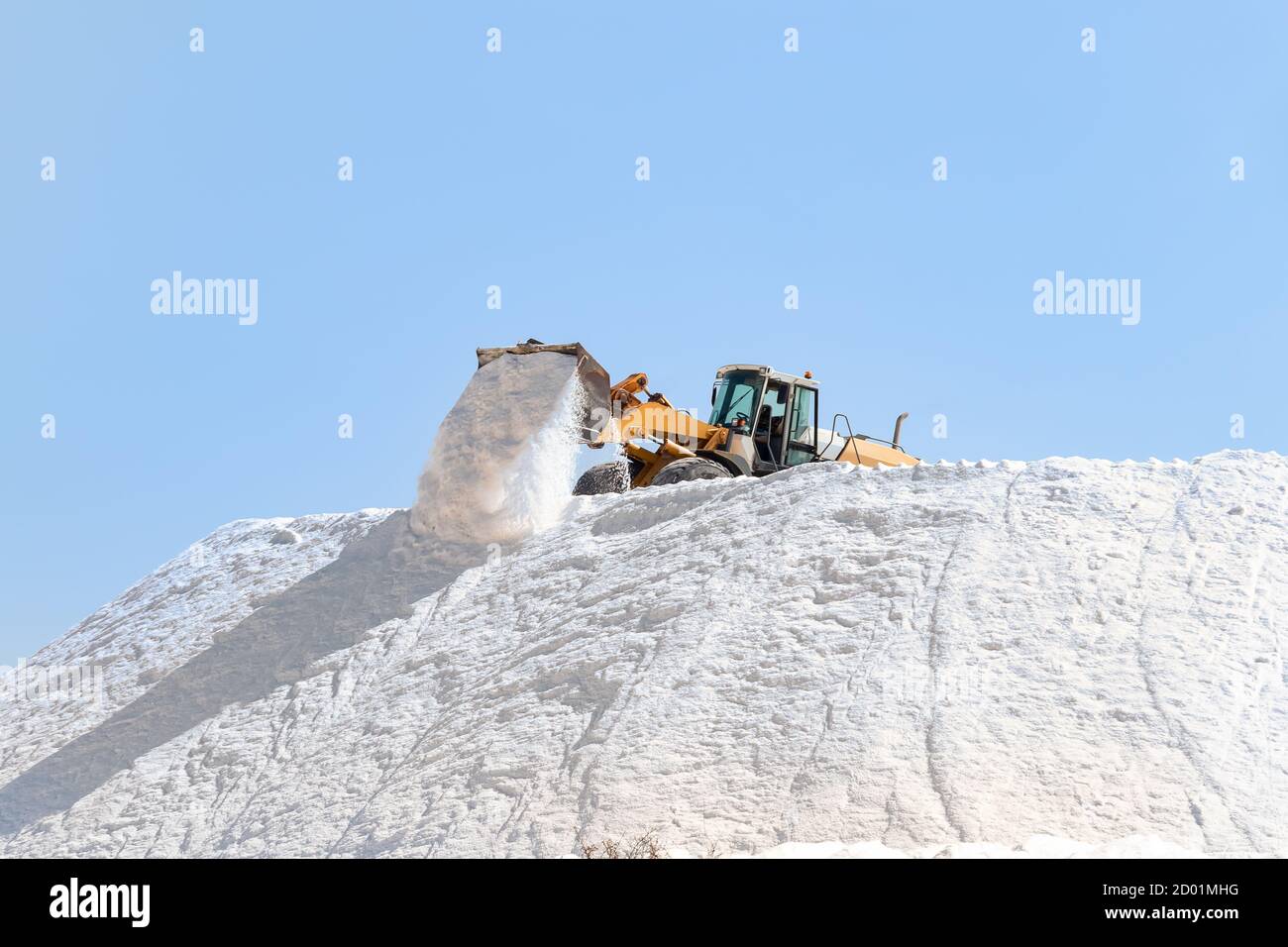 Salzproduktion. Bagger arbeiten in einem riesigen Pfahlsalz in Salzwerken. Meersalz, das durch die Verdunstung von Meerwasser entsteht. Stockfoto