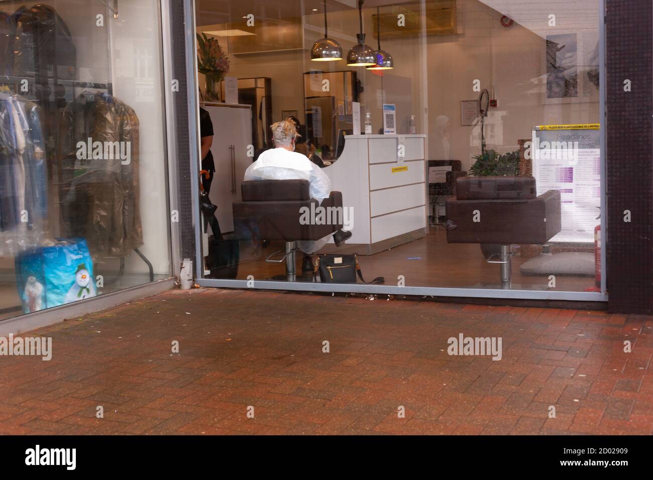 Business as usual / Covid 19 mal / Blick in einen Friseursalon und Rückansicht eines sitzenden Kunden und Stylist. Hohe Auflösung. Copyspace Stockfoto