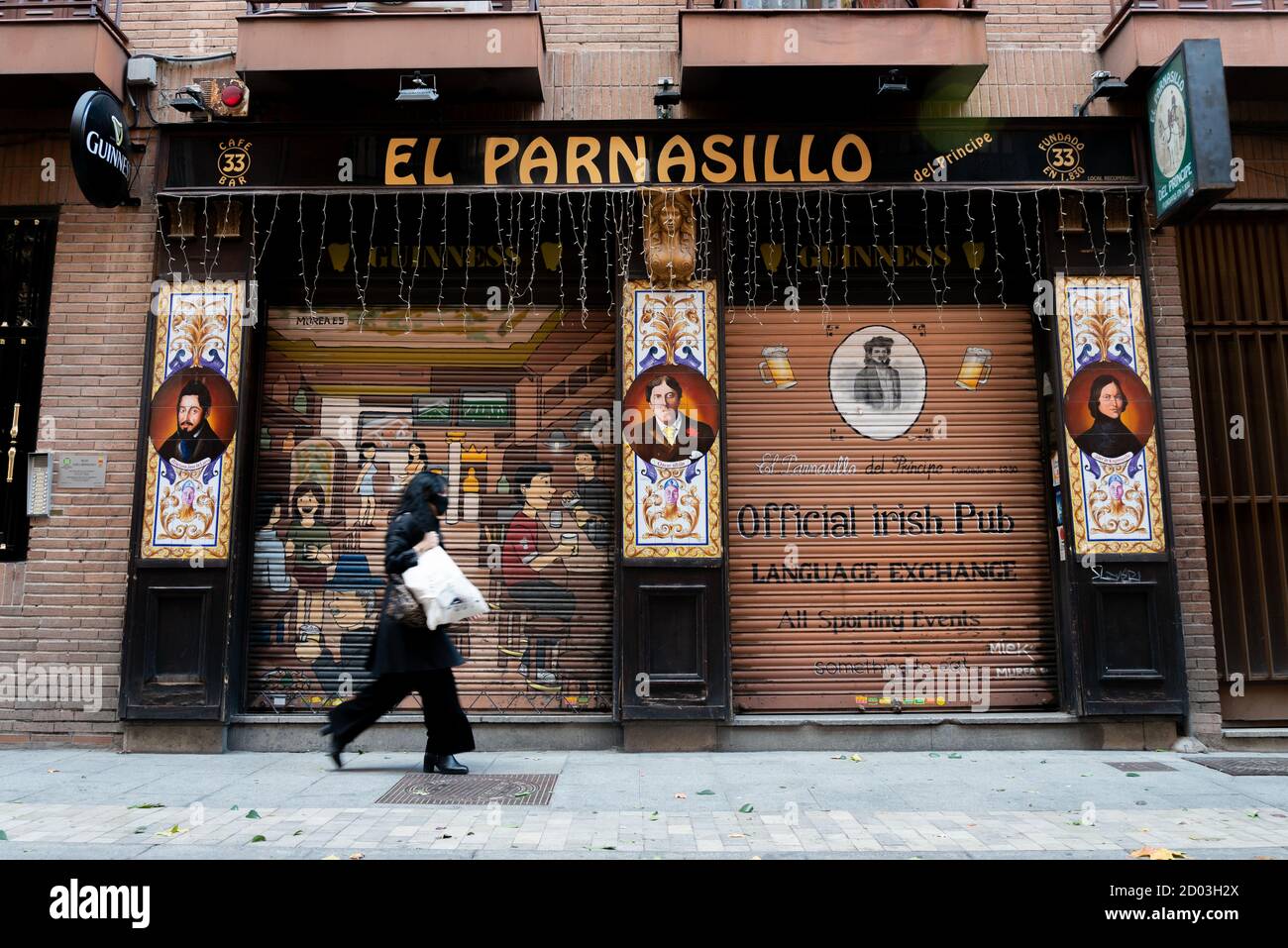Eine Frau mit Gesichtsmaske geht an einem geschlossenen Restaurant vorbei.heute sind in Madrid die von der Regierung geforderten Haftmaßnahmen zur Bekämpfung der Pandemie in Kraft getreten. Beschränkung des ein- und Ausgangs in Wohngebieten, Reduzierung der sozialen und familiären Versammlungen auf maximal sechs Personen, Restaurants schließen um 10 Uhr und haben eine maximale Kapazität von 50%. Stockfoto