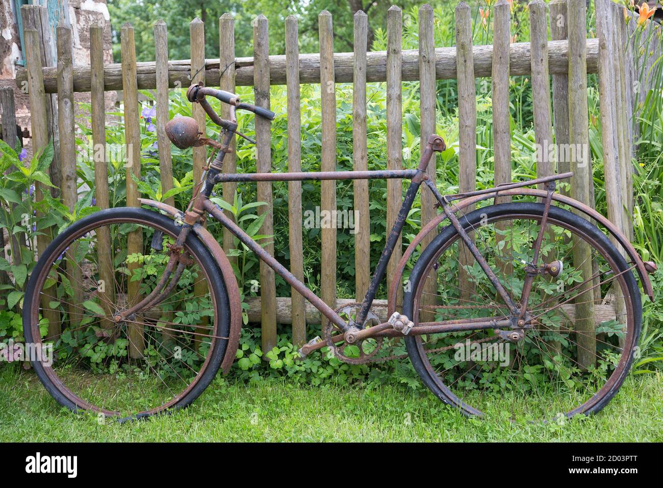 Altes rostiges Fahrrad, das an einen Holzzaun gelehnt ist Stockfoto