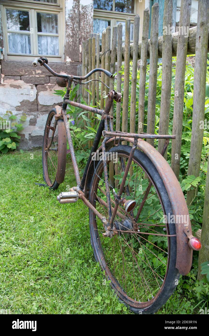 Altes rostiges Fahrrad, das an einen Holzzaun gelehnt ist Stockfoto