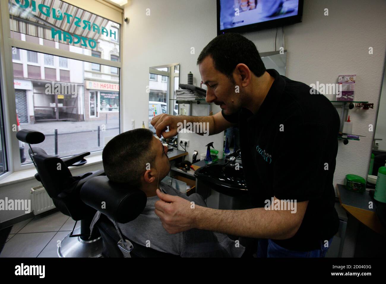 Oezcan Yildirim, ein türkischer Friseur arbeitet in seinen Friseurladen in  Keupstrasse in sogenannten "Klein-Istanbul" Köln 10. April 2013. Der  Friseur wurde völlig zerstört und 22 Personen wurden verletzt, am 9. Juni  2004,