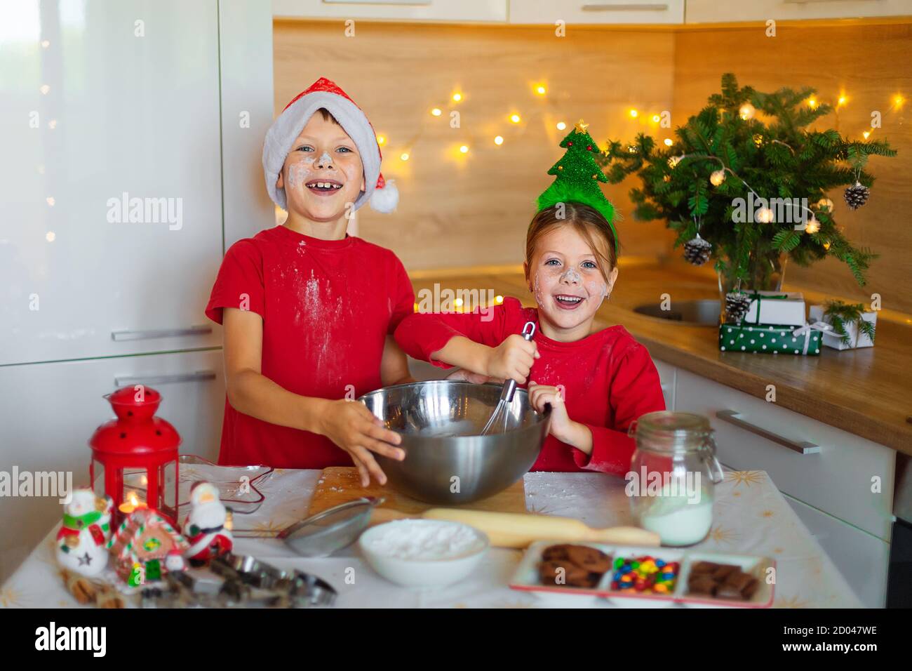 Glückliche Kinder bereiten am Vorabend des neuen Jahres Lebkuchen zu. Junge und Mädchen in der Küche warten auf Weihnachten. Kinder machen Urlaub Cookies zu Hause. Stockfoto