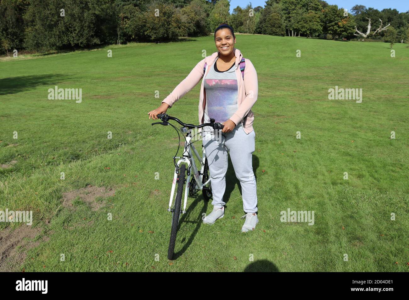 Junge Mixed Race Frau stehend und lächelnd mit dem Fahrrad. Stockfoto
