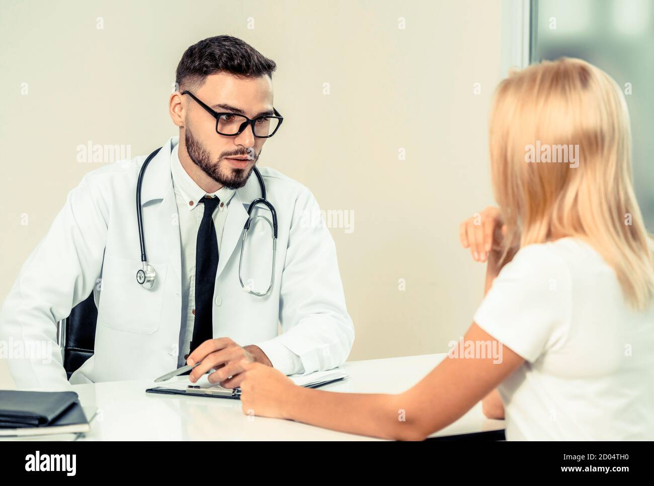 Männlicher Arzt spricht mit weiblichen Patienten im Krankenhaus. Gesundheitswesen und medizinische Betreuung. Stockfoto