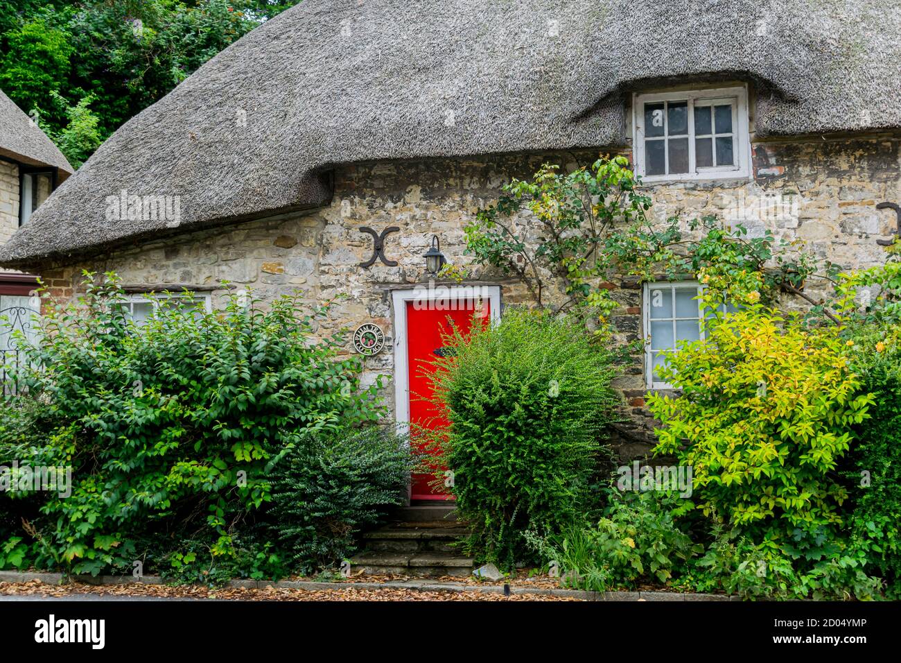 West Lulworth, Vereinigtes Königreich - 19 July 2020: Schönes reetgedeckte Häuschen mit roter Tür und Fensterläden, einzigartiges Dorset buntes Haus Stockfoto