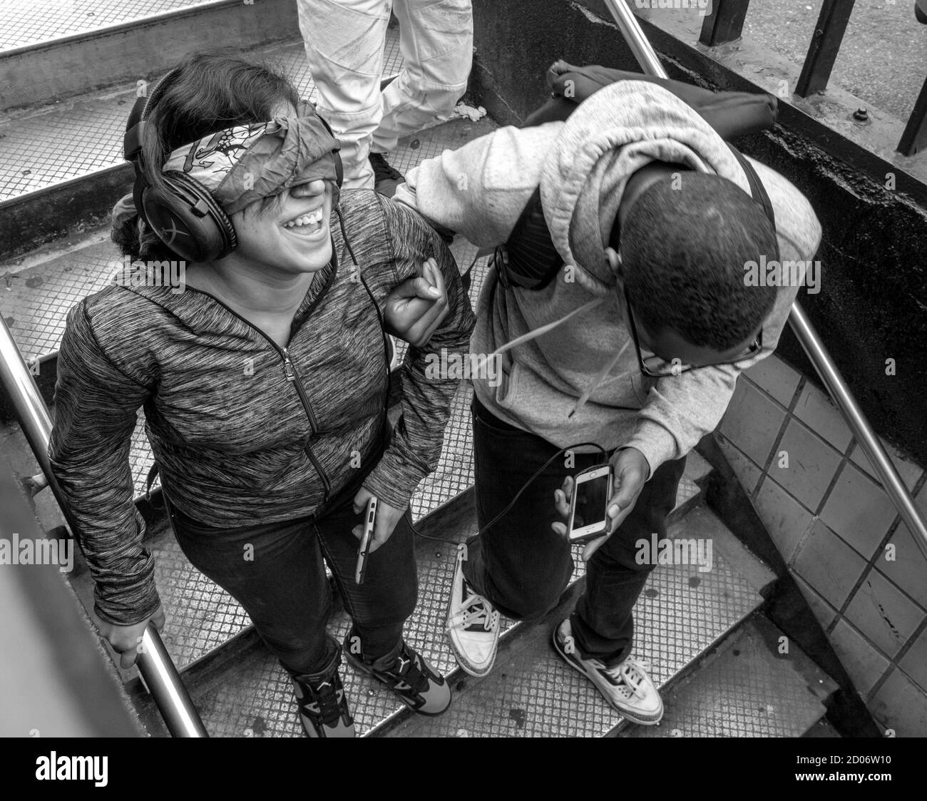 Ein junger Mann führt eine junge Frau mit verbundenen Augen die U-Bahn-Stufen hinunter. Foto von Liz Roll Stockfoto
