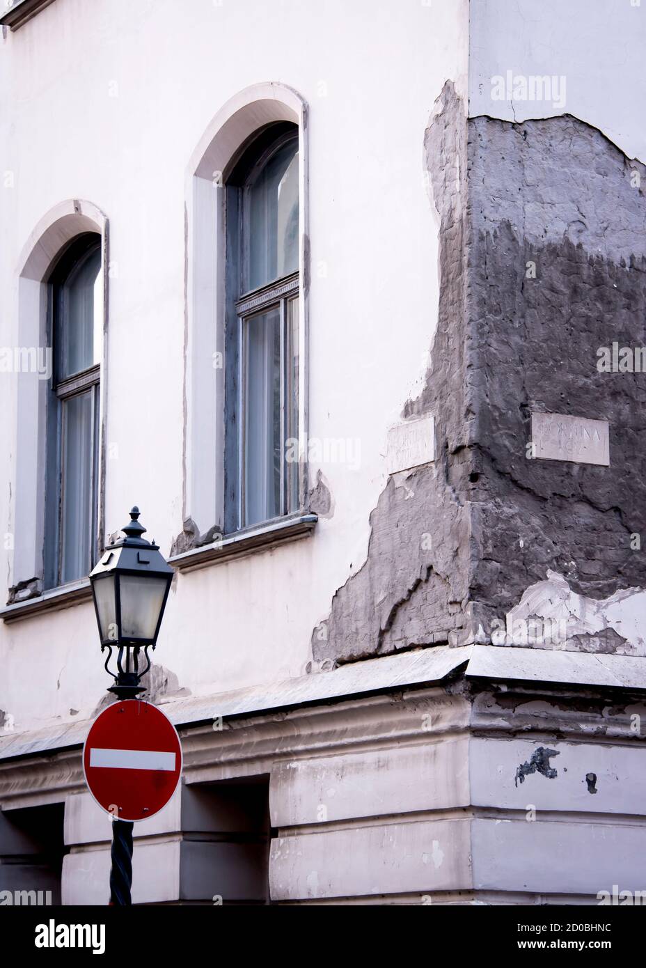 Die Ecke eines Gebäudes mit zerbröckeltem Putz, einem Straßenschild und einer Laterne in Budapest Stockfoto