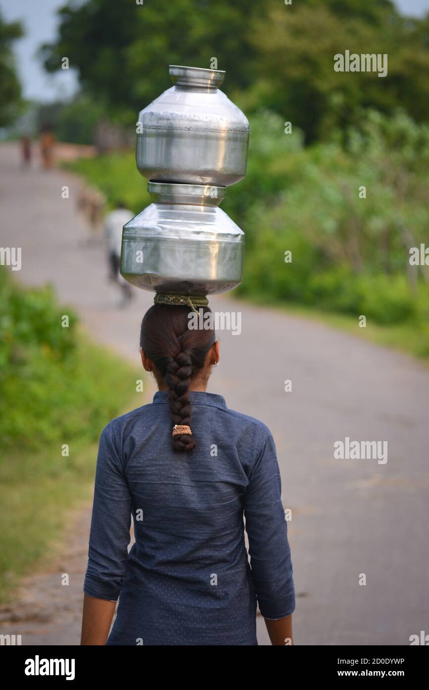 Unbekannte indische Mädchen tragen Wasser auf ihren Köpfen in traditionellen Töpfen von gut, jeden Tag Frauen gehen wenige Kilometer, um es wegen der Dürre zu bekommen. Stockfoto