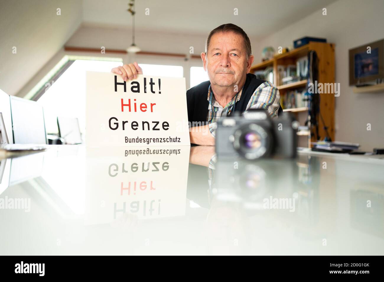 Barum, Deutschland. September 2020. Jürgen Ritter, Fotograf, sitzt an einem Tisch mit einem Replik-Schild in der Hand. Anlässlich des 30. Jahrestages der Wiedervereinigung zeigt Ritter, der im Landkreis Uelzen lebt, nun im Internet, wie sechzig prominente Orte vor der Wiedervereinigung aussahen und wie sie sich seitdem verändert haben. (To dpa 'Places in Change: Border Photographer keeps Memories of Division alive' vpm 03.10.2020) Quelle: Philipp Schulze/dpa/Alamy Live News Stockfoto