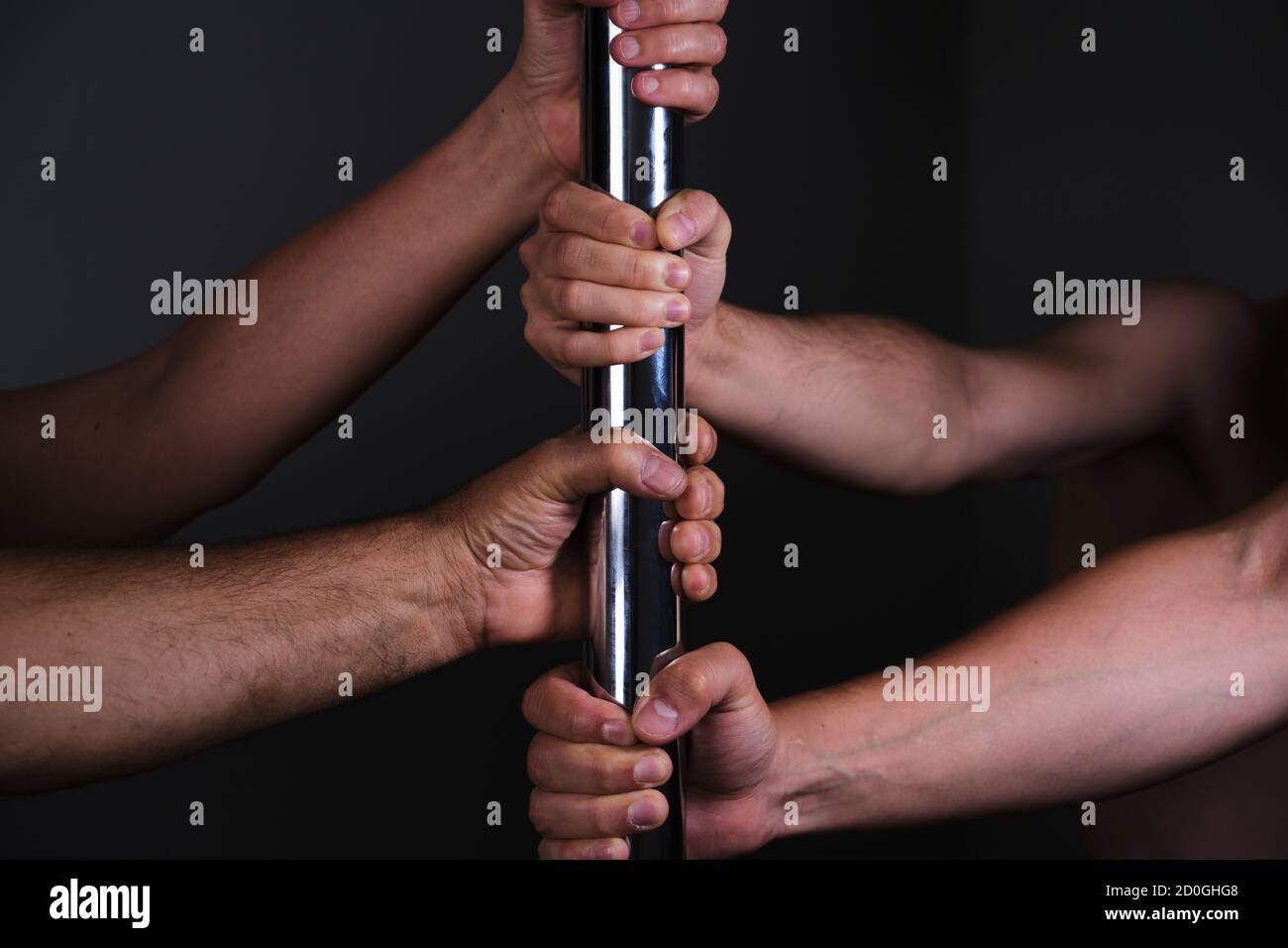 Vier Hände mit einer Stabtanz. Dunkler Hintergrund. Stockfoto