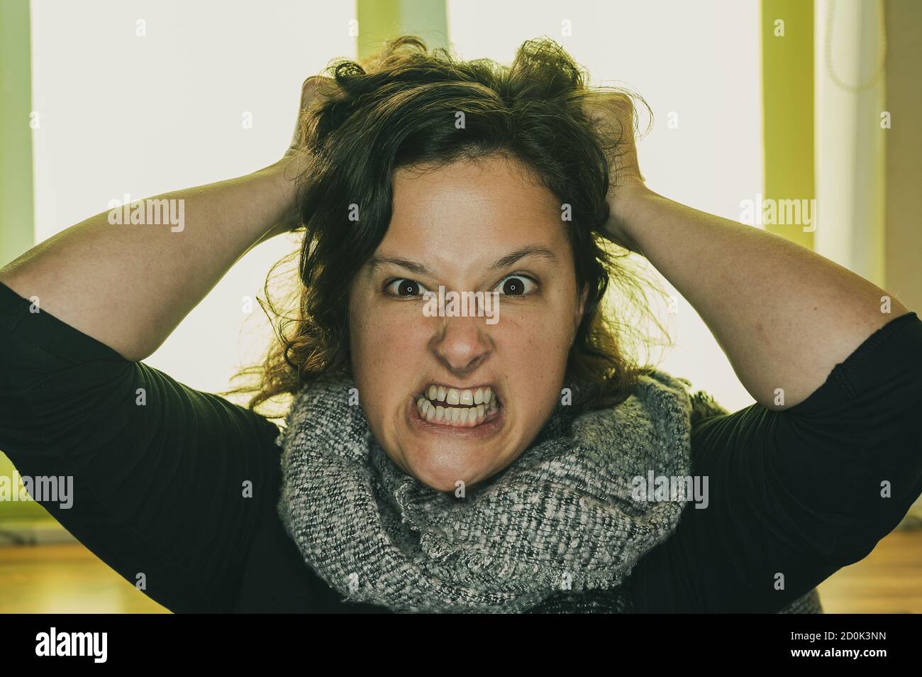 Eine junge Frau mit einem wütenden Blick zieht an ihren Haaren. Stockfoto