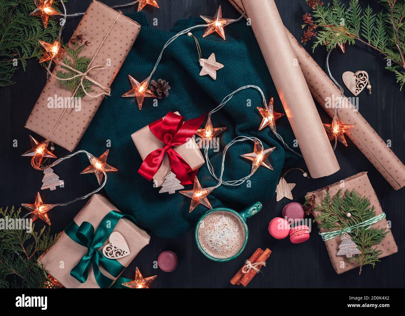 Weihnachtsgeschenkschachteln in Kraftpapier verpackt und mit Atlas Bogen und Zypresse auf rustikalem Holzhintergrund dekorieren. Flach liegend. Draufsicht Stockfoto