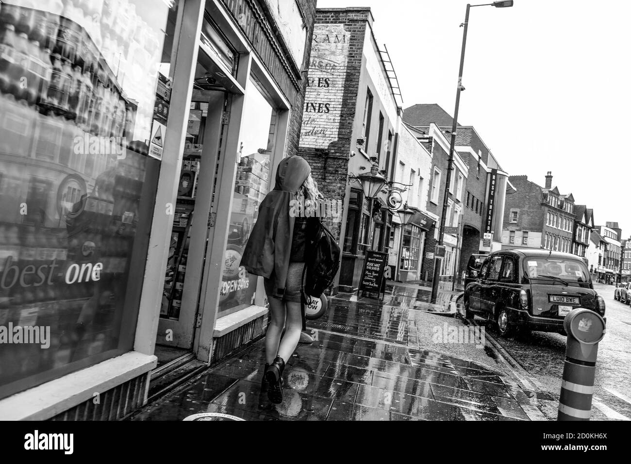 Junge Frau trägt EINEN kurzen Rock und Stiefel zu Fuß in Der Regen In Schwarz Und Weiß Stockfoto