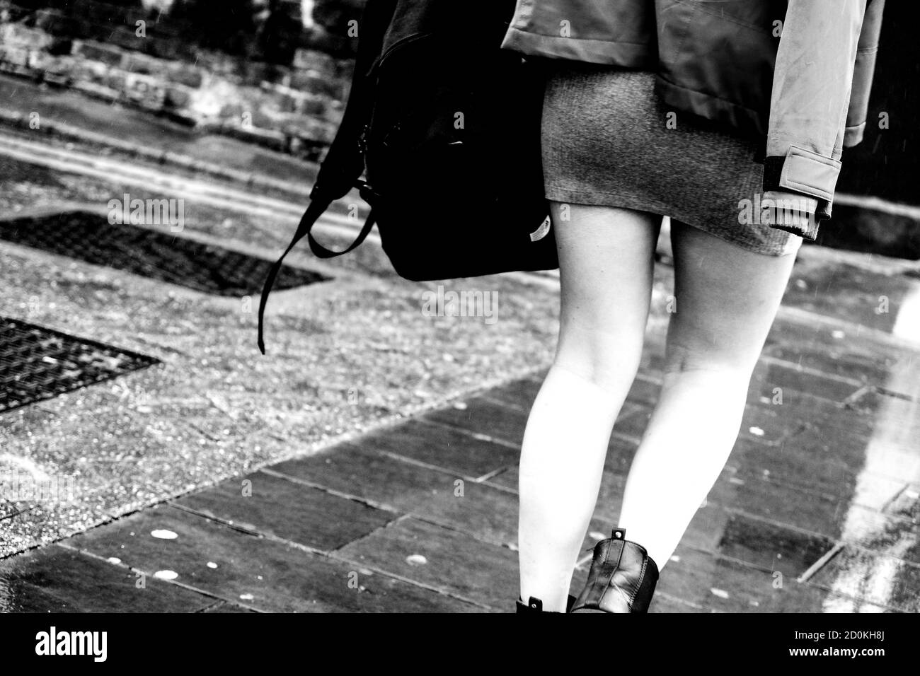 Junge Frau, die im Regen nach Hause geht, trägt EINEN kurzen, eng anliegendem Minirock, Nahaufnahme in Schwarz und Weiß Stockfoto