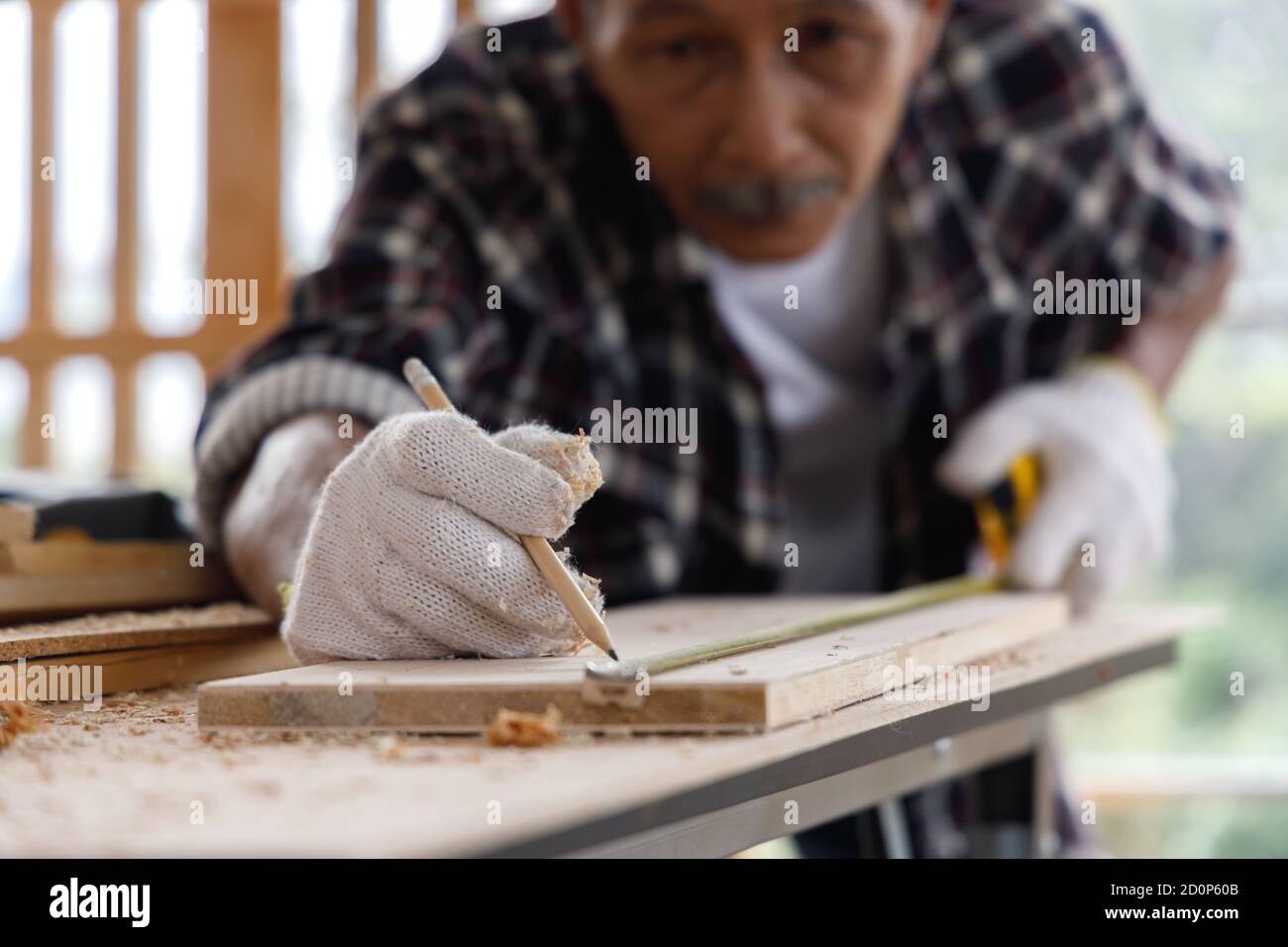 Nahaufnahme Senior Mann Verwenden Sie Maßband, um die Breite der Holzdiele in der Schreinerei zu messen. Stockfoto