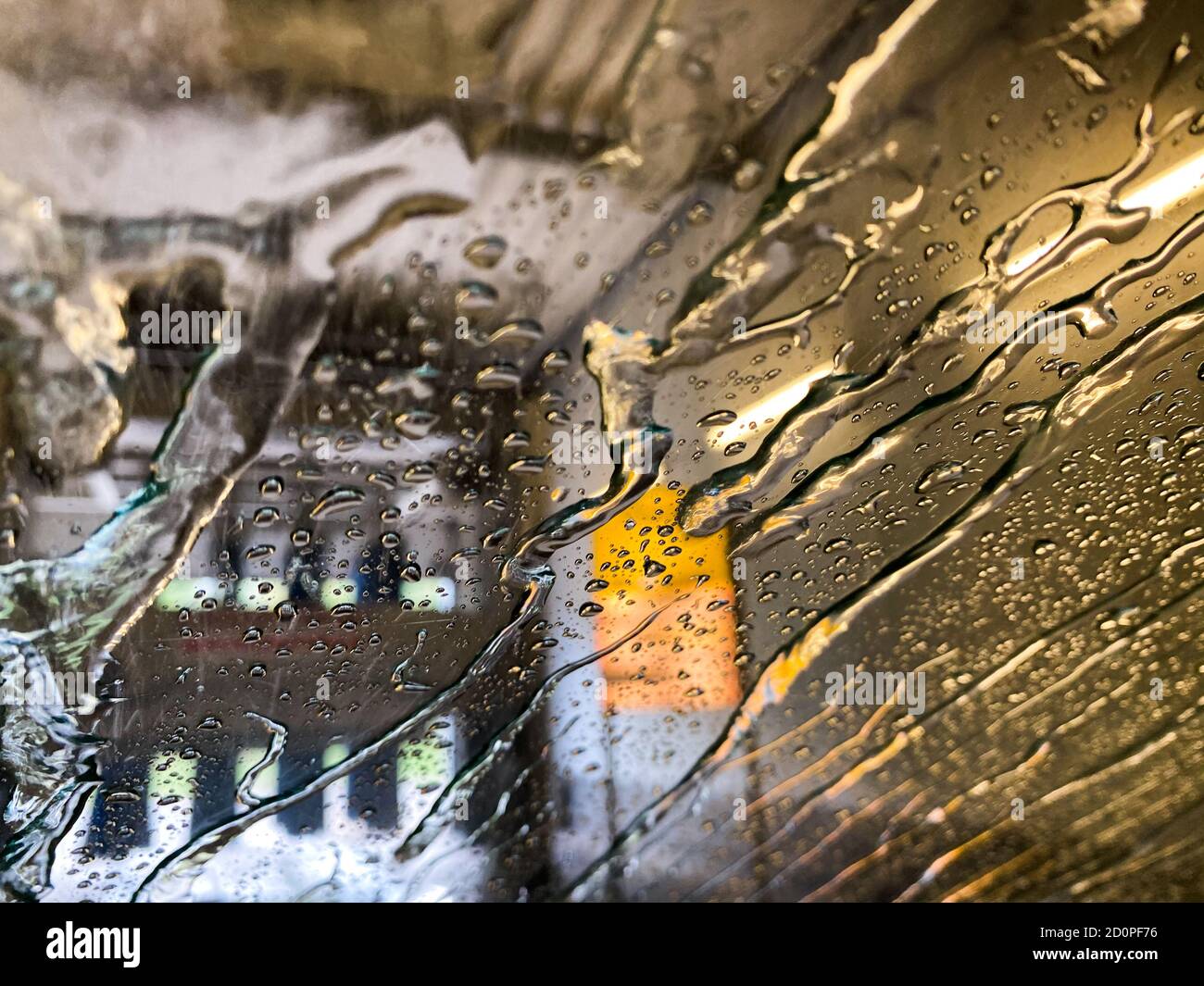 Blick von innen auf Windschutzscheibe mit Wassertropfen und Streifen In automatischer Waschanlage Stockfoto
