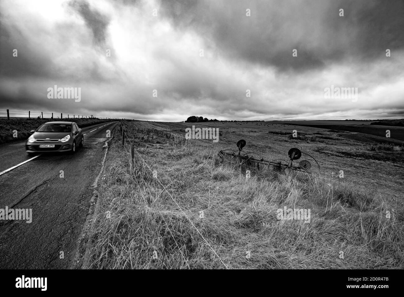 Ein Auto, das einen alten Heuzettler oder Spinner auf Hügeln über der Wiltshire-Stadt von Mere passiert, an einem nassen und windigen Tag, als Storm Alex ankommt. Digitale Farbe p Stockfoto