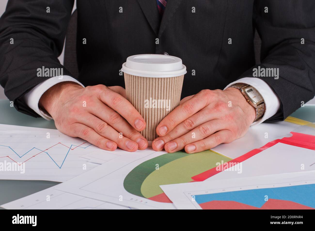 Männliche Hände mit Kaffeetasse und Geschäftsunterlagen auf dem Tisch. Stockfoto