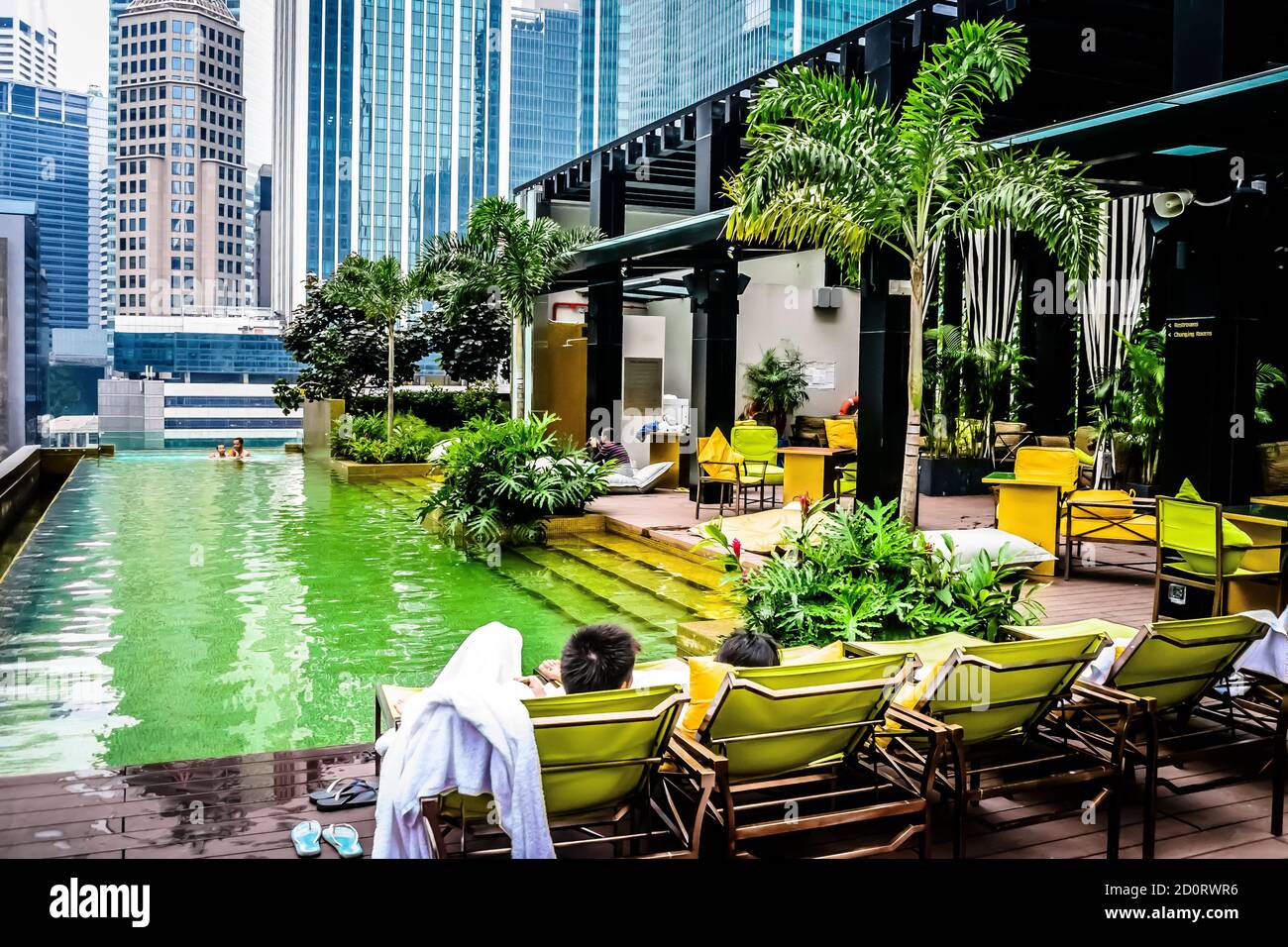 Dachgarten-Swimmingpool in der Stadt mit Sonnenbänken, Liegestühlen und Sonnenanbeter Stockfoto