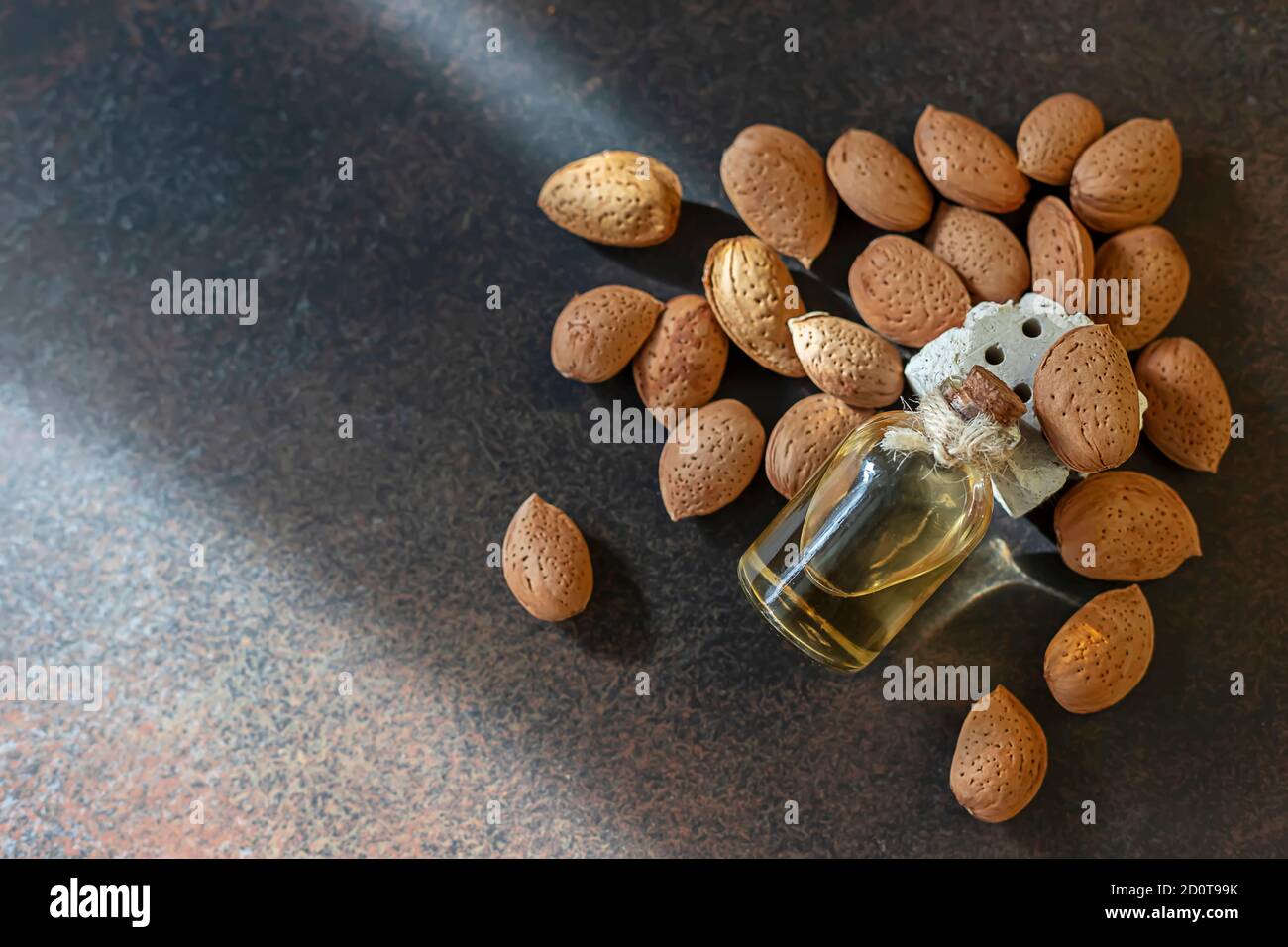 Glasflasche mit Mandelöl und Mandeln auf dunklem Hintergrund. Stockfoto