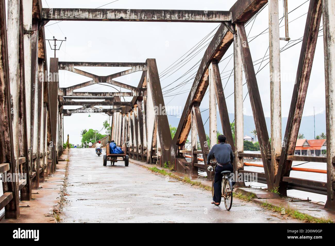 Khmer Menschen Fahrrad fahren und Motorrad über die alte Brücke, wurde aus der französischen Kolonialzeit in Kampot, Süd-Kambodscha gebaut. Stockfoto