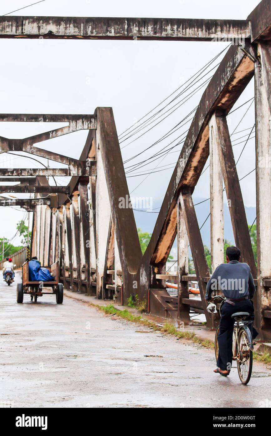 Khmer Menschen Fahrrad fahren und Motorrad über die alte Brücke, wurde aus der französischen Kolonialzeit in Kampot, Süd-Kambodscha gebaut. Stockfoto