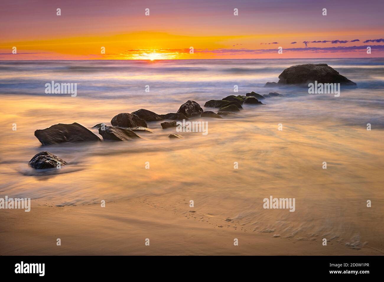 Neblige verschwommene Wellen und Surfen mit Felsen bei Sonnenaufgang, Narragansett, Rhode Island USA Stockfoto