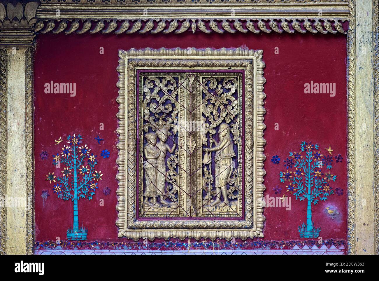 Geschnitztes Scheinfenster flankiert von Glasmosaikbäumen, Tempel Wat Souvannakhirii, Luang Prabang, Laos, Asien Stockfoto