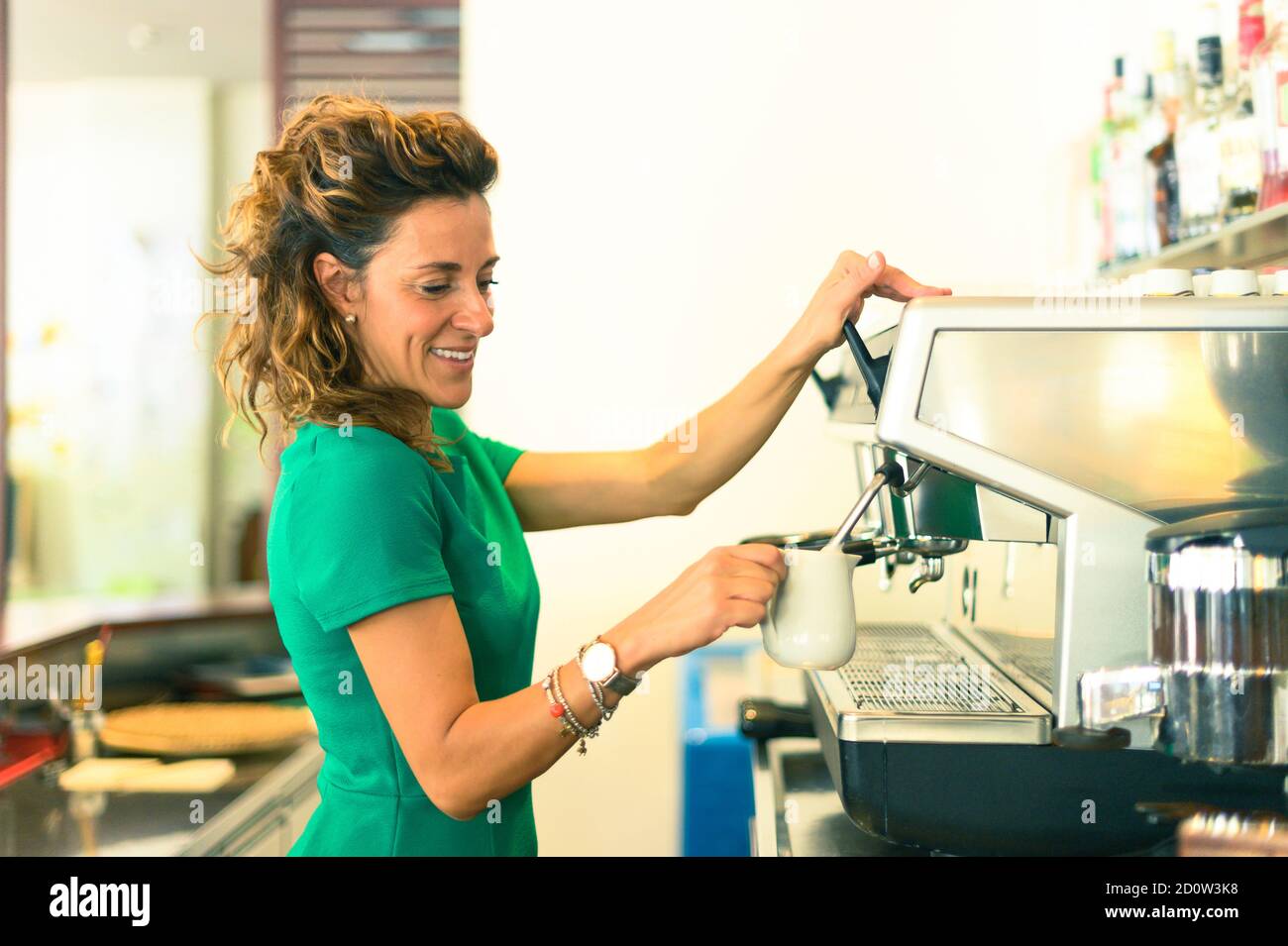 Barkeeper Dame, Vorbereitung Kaffee trinken mit Espresso-Maschine im Shop Café - Frau halten Porzellan Milchkrug in der Hand - Lifestyle im Coffee Shop Konzept Stockfoto