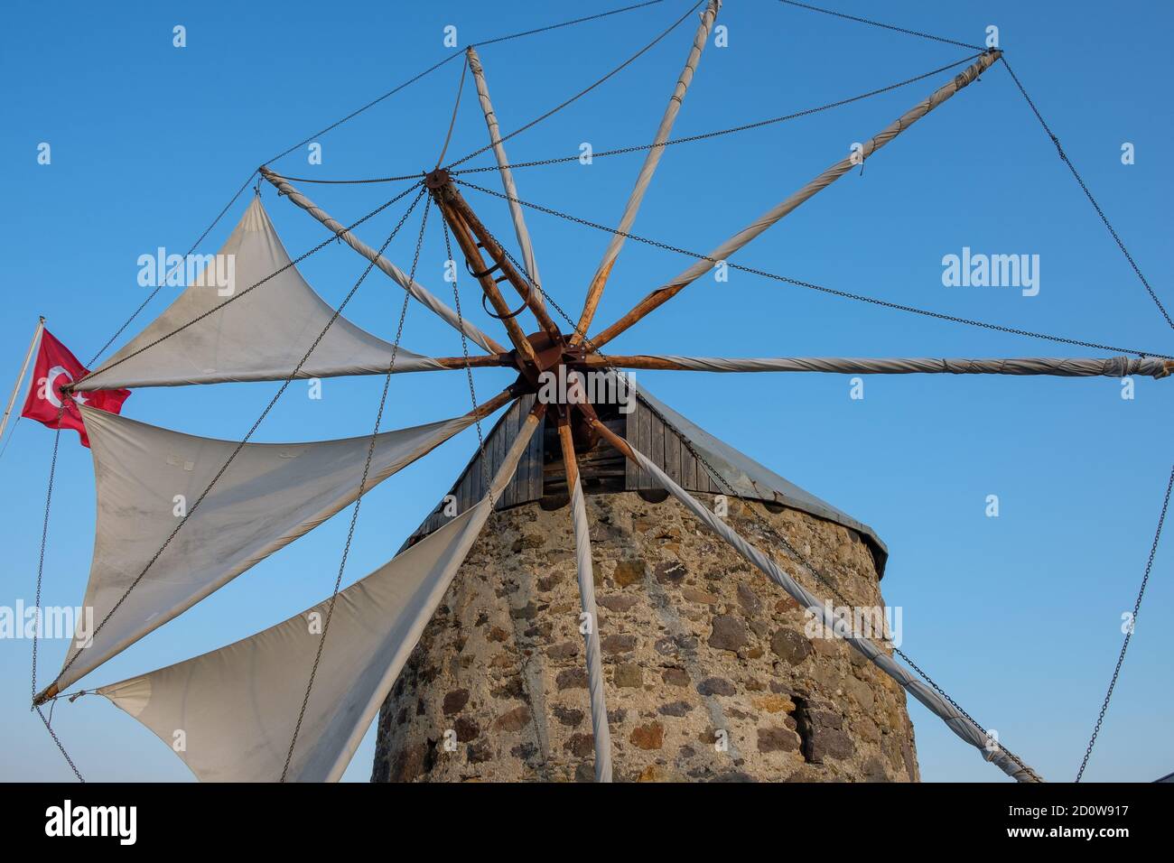 Alte Steinwindmühle, blauer Himmel und die türkische Flagge Stockfoto
