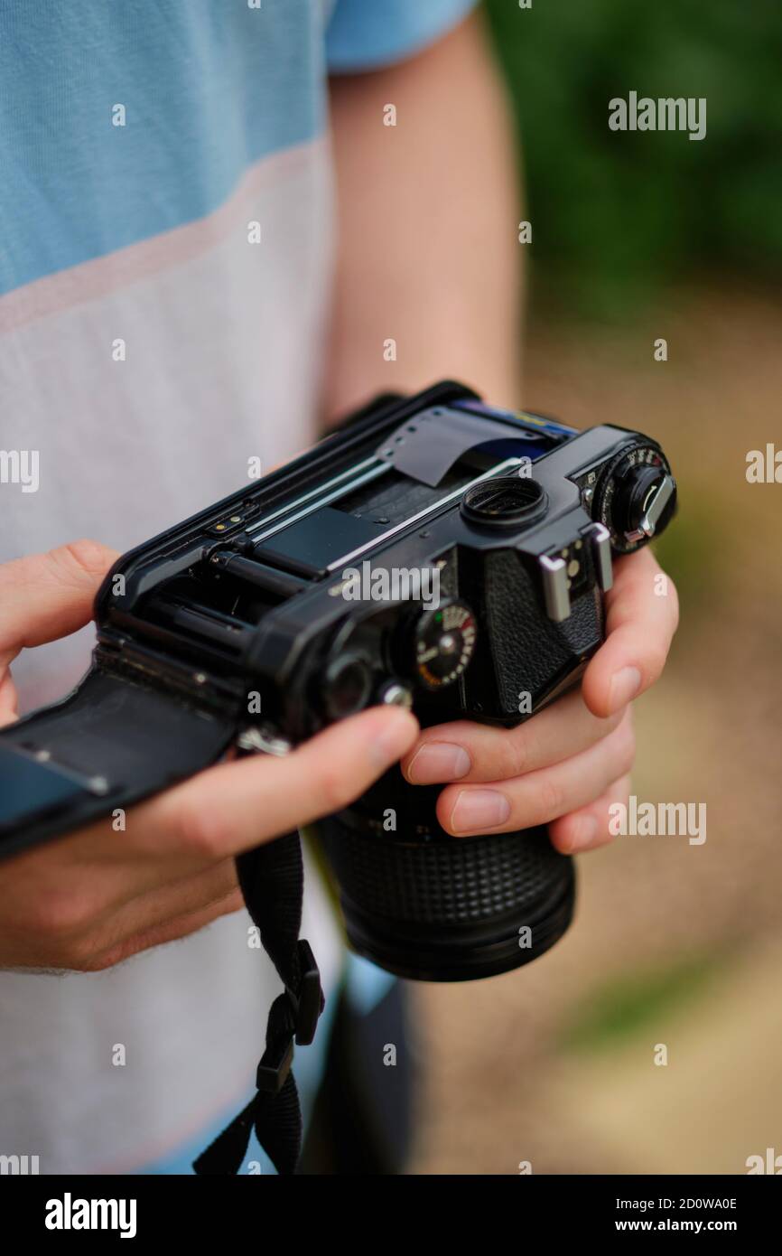 Ein junger Mann lädt Fotofilm in eine analoge Kamera, ein Medium, das in den letzten Jahren ein Wiederaufleben erleben kann (MR) Stockfoto