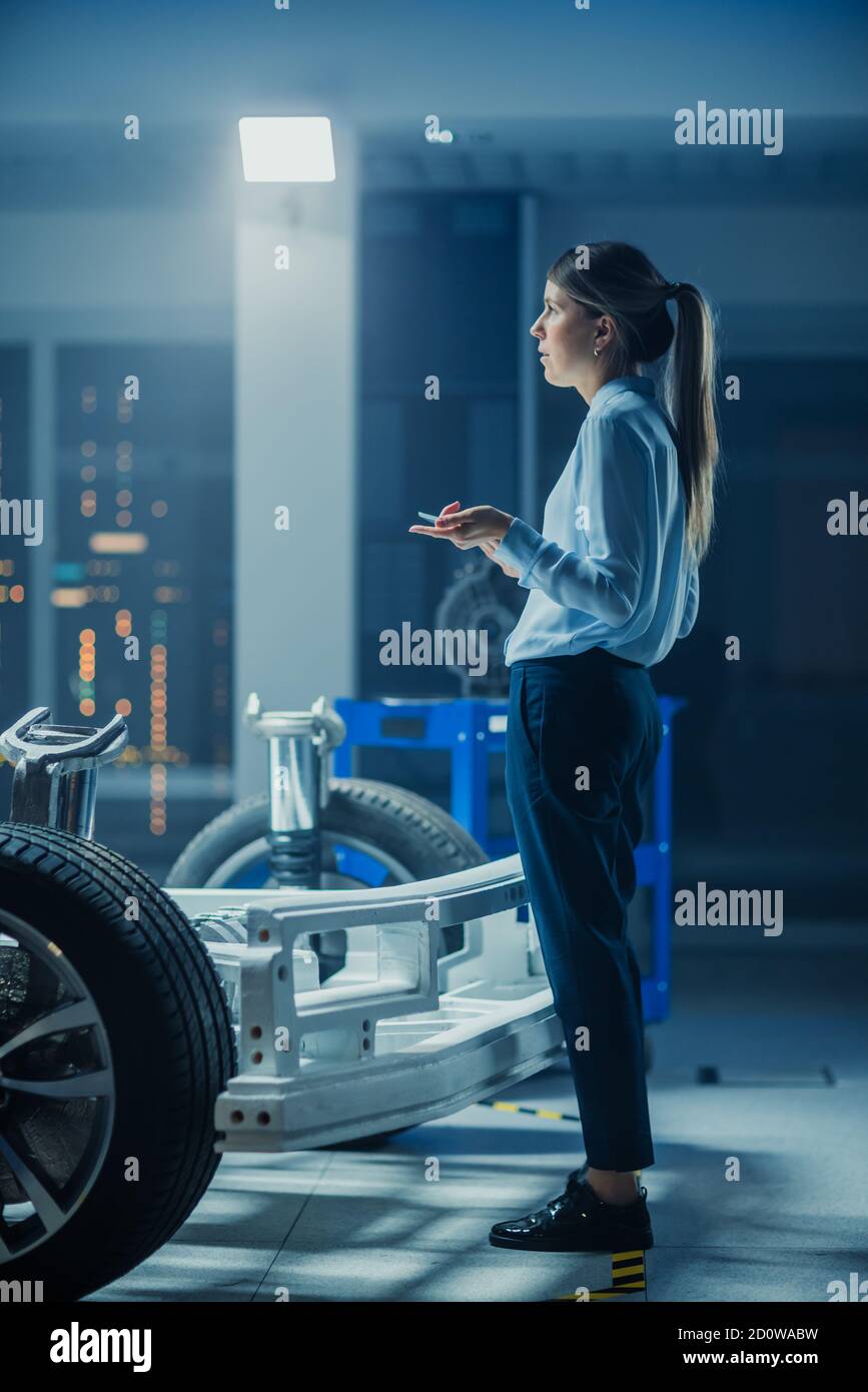 Automotive Design Engineer Denken Über Elektro-Auto-Chassis-Prototyp. In Innovation Laboratory Facility Konzept Fahrzeug Rahmen Umfasst Räder Stockfoto