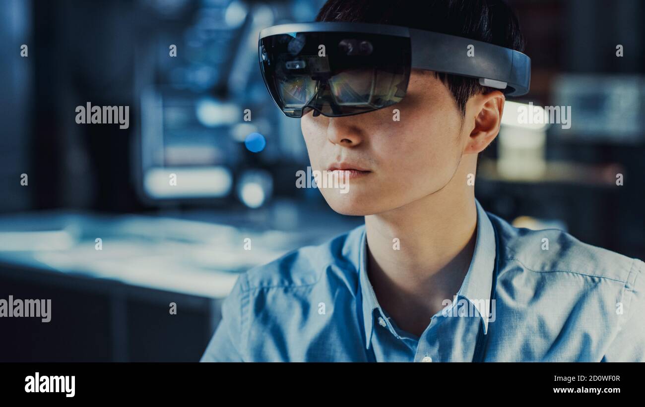 Professionelle japanische Elektronik-Entwicklungsingenieur in Blau Shirt trägt Ein Virtual Reality-Headset und ein Blick auf die High-Tech Forschung Stockfoto