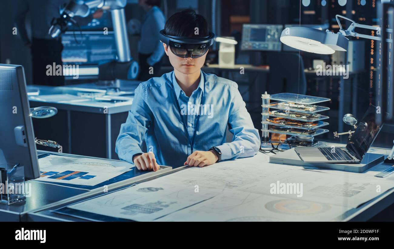 Ein professioneller japanischer Entwicklungsingenieur arbeitet in einem AR-Headset mit Zeichnungen für virtuelle Grafiken im High Tech Research Laboratory Stockfoto