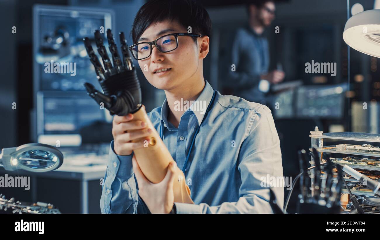 Futuristischer prothetischer Roboterarm, der von einem professionellen Japaner getestet wird Entwicklungsingenieur in einem High-Tech-Forschungslabor mit modernen Computer Stockfoto