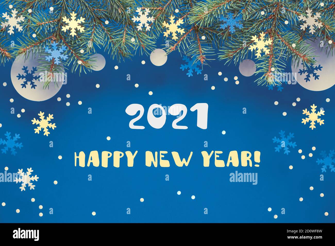 Weihnachtshintergrund mit Tannenzweigen und Papierdekorationen auf dunkelblauem Hintergrund. Text Frohes Neues Jahr 2021. Stockfoto