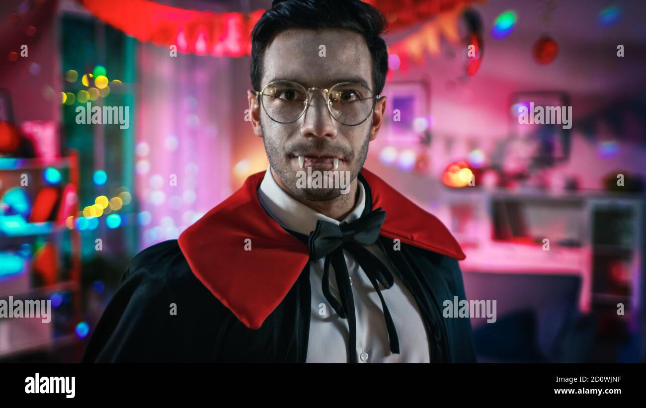 Halloween Kostüm Party: Porträt von Graf Dracula gruselig lächelnd, zeigt seine tödlich blutigen Fangs. Im Hintergrund thematisch dekoriertes Zimmer mit Stockfoto