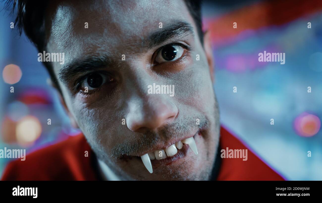 Halloween Kostüm Party: Nahaufnahme Porträt von Graf Dracula gruselig lächelnd, zeigt seine tödlich blutigen Fangs, tut seinen tödlichen Biss. Im Hintergrund Stockfoto
