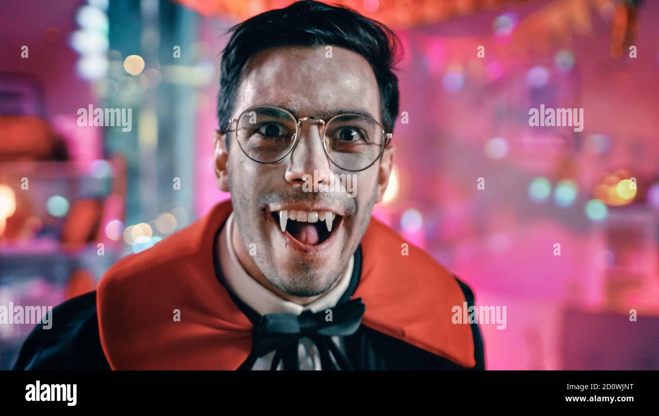 Halloween Kostüm Party: Porträt von Graf Dracula gruselig lächelnd, zeigt seine tödlich blutigen Fangs. Im Hintergrund thematisch dekoriertes Zimmer mit Stockfoto