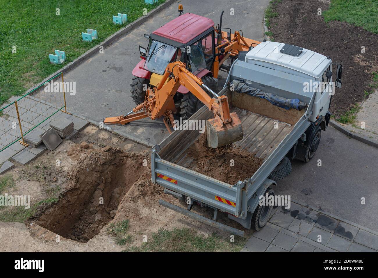 Smolensk, Russland - 08/15/2018: Ein Traktor mit Bagger gräbt eine Grube und Lasten Sand der LKW-Karosserie. Stock Foto. Stockfoto