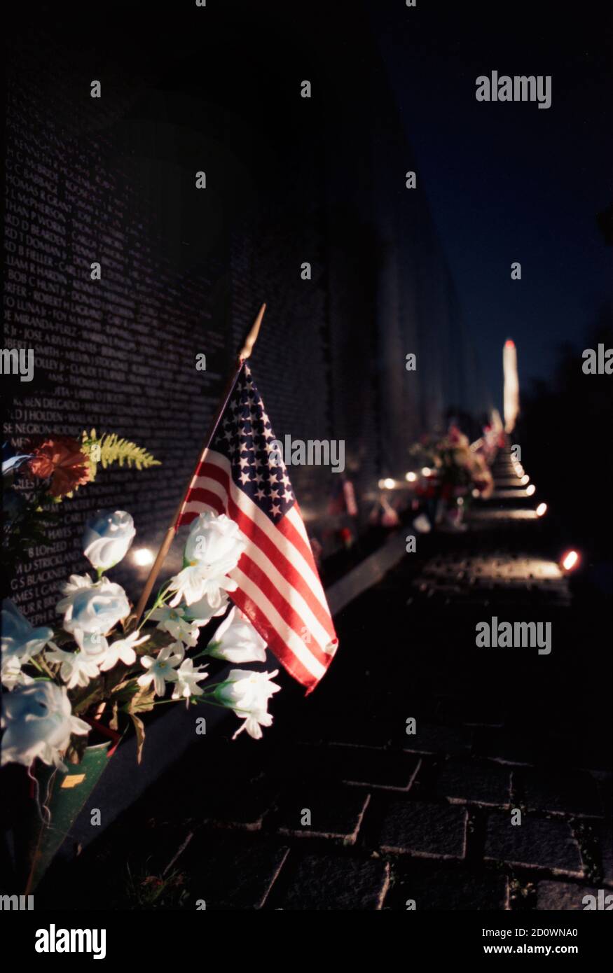 Ein bewegender Tribut an diejenigen, die mit ihrem Leben geopfert haben Während des Vietnamkrieges mit Blumen und einer amerikanischen Flagge Am Vietnam Veterans Memorial Stockfoto