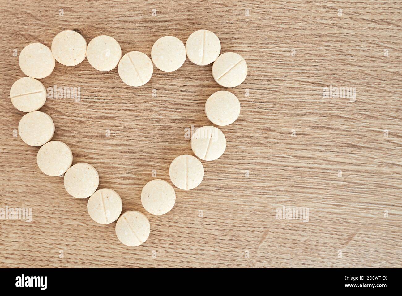 Weiße Herzform aus Pillen für die Therapie, Konzept der Behandlung und Gesundheitsversorgung auf Holzhintergrund. Medizinisches Banner, Kopierbereich Stockfoto