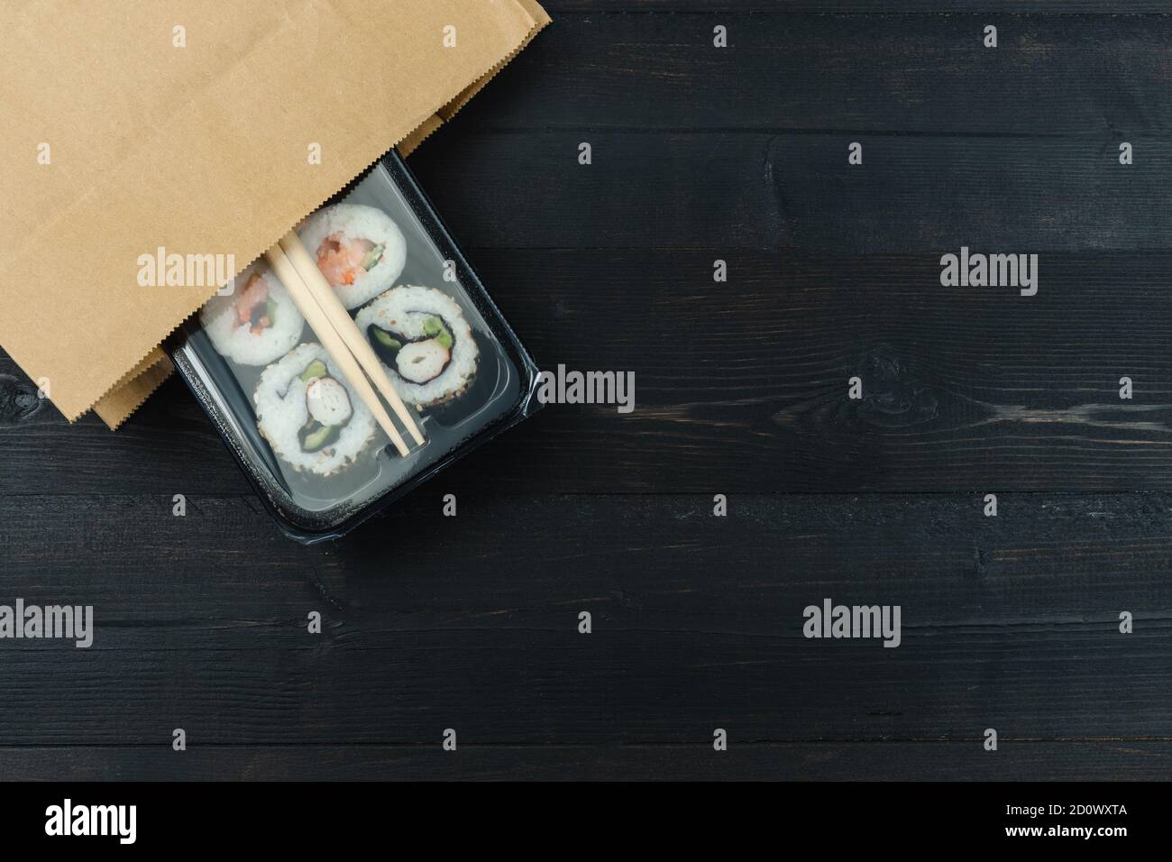 Papiertüte Sushi Tablett auf schwarzem Holzhintergrund. Speicherplatz kopieren. Food-Konzept. Stockfoto