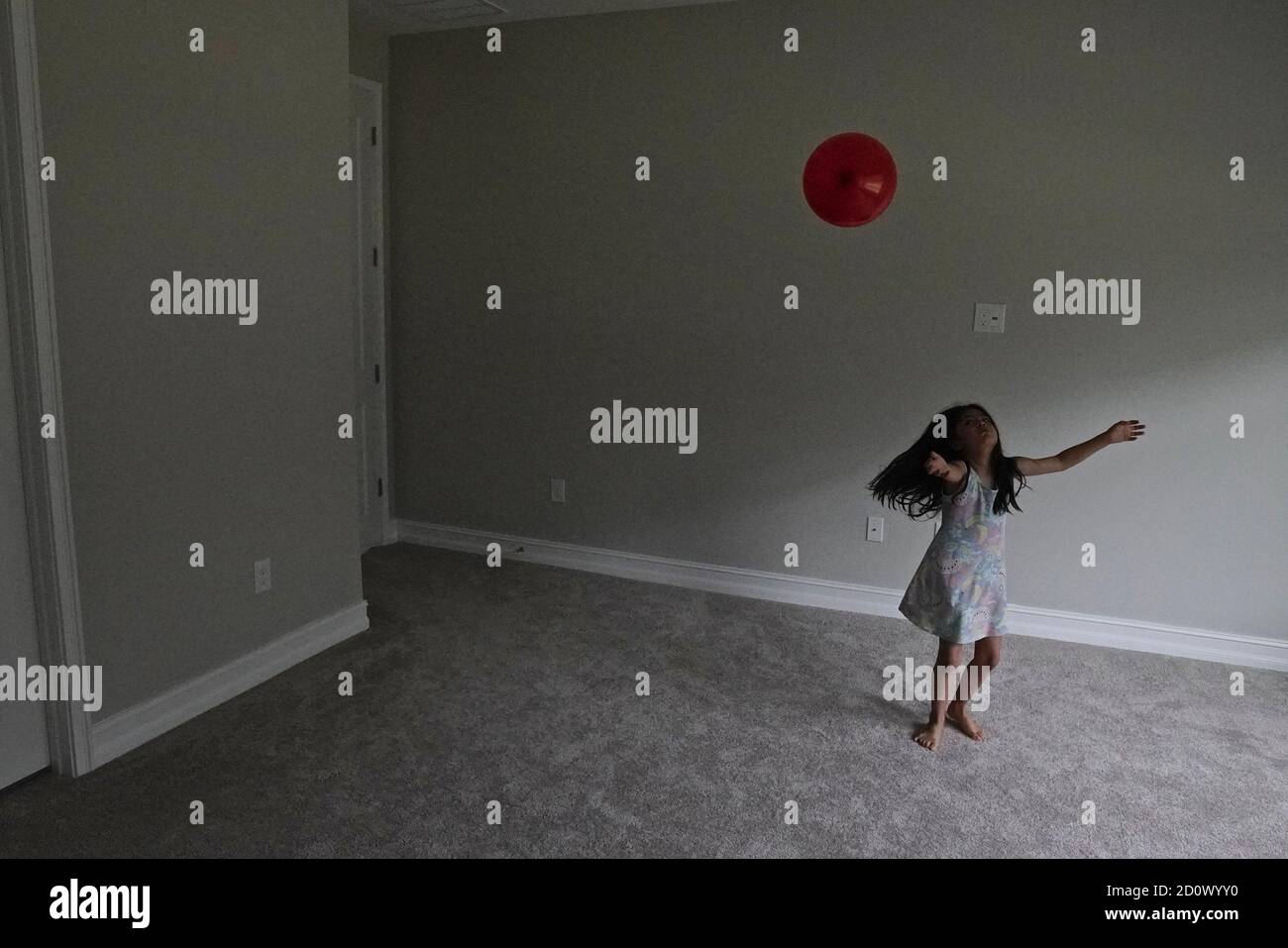 Fünf Jahre altes Mädchen spielt mit einem roten Ballon in Ein leerer Raum Stockfoto