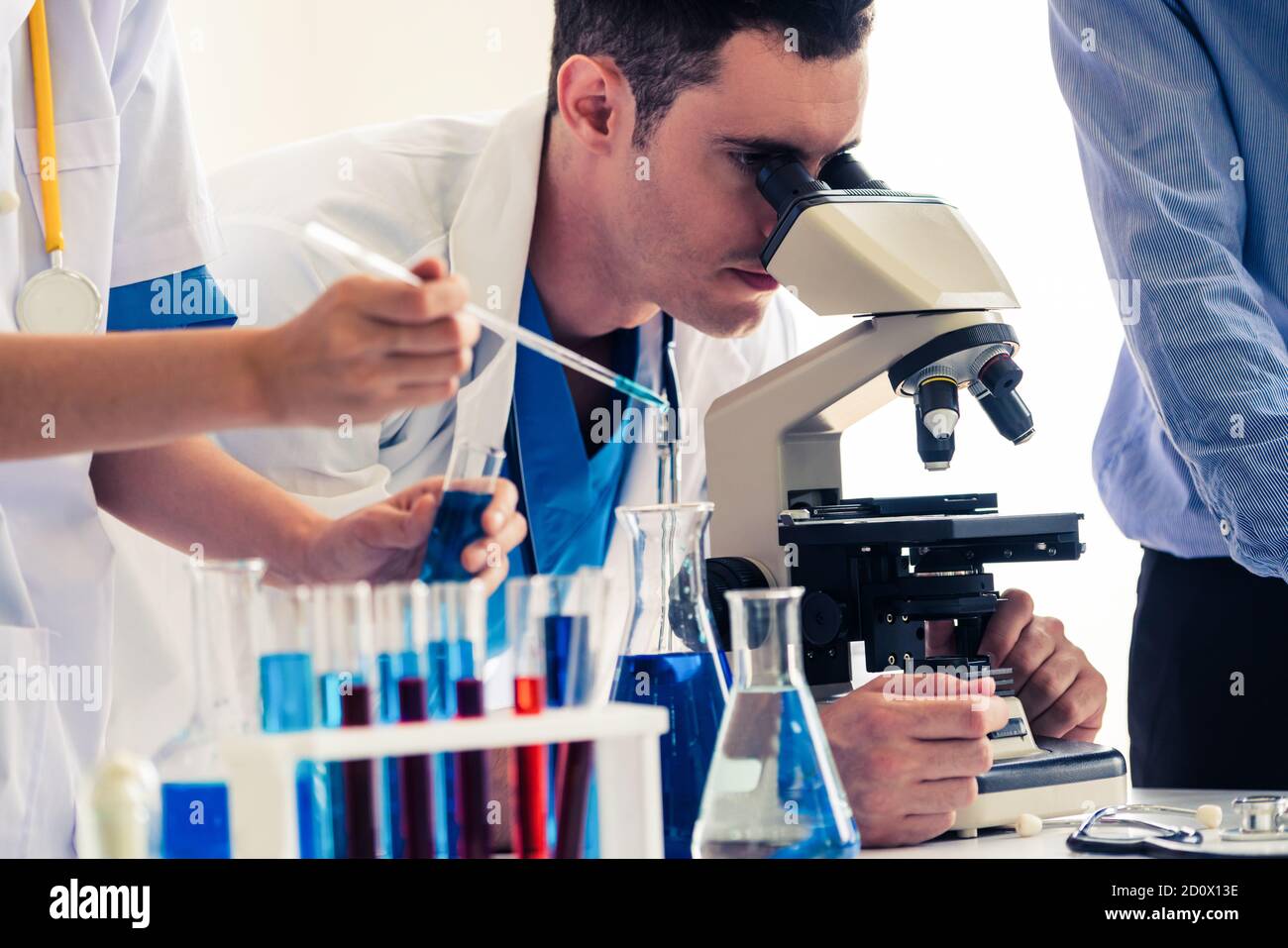 Gruppe von Wissenschaftlern mit Labormantel, die im Labor arbeiten, während sie biochemische Proben in Reagenzglas und wissenschaftlichen Instrumenten untersuchen. Wissenschaft Stockfoto