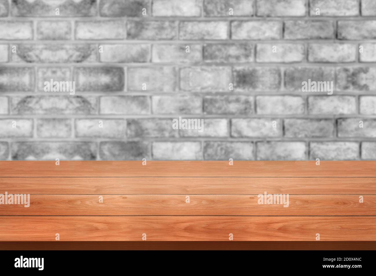 Holztisch vor rustikalen Backstein Wand verwischen Hintergrund mit leeren Kopieplatz auf dem Tisch für Produkt-Display Mockup. Montage im Retro-Design Stockfoto