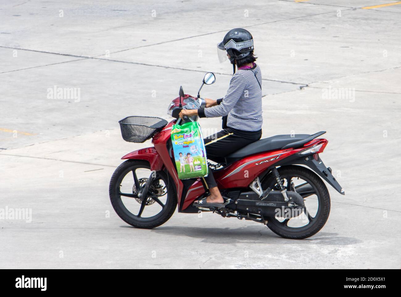 SAMUT PRAKAN, THAILAND, JULI 23 2020, Frau mit Tasche fährt ein Motorrad Stockfoto