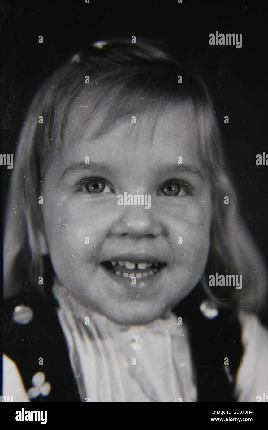 Feine 70er Jahre Vintage Schwarz-Weiß-Fotografie von einem frisch gesichtigen glücklichen kleinen Mädchen. Stockfoto