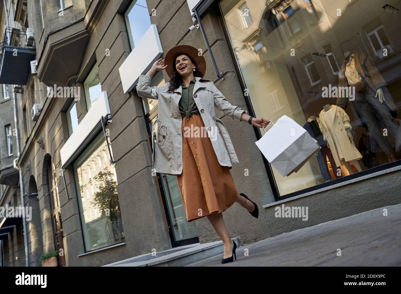 Elegante Dame. Junge schöne aufgeregt Frau zu Fuß Stadtstraßen mit Einkaufstaschen, Blick zur Seite und lachen, in voller Länge. Mode, Shopaholismus, Menschen Lifestyle-Konzept Stockfoto